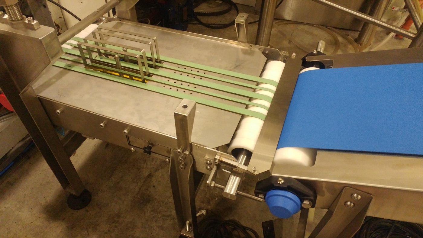 Fotografía real del peine acumulador retráctil funcionando entre las bandas verdes en la planta de Sigma Line